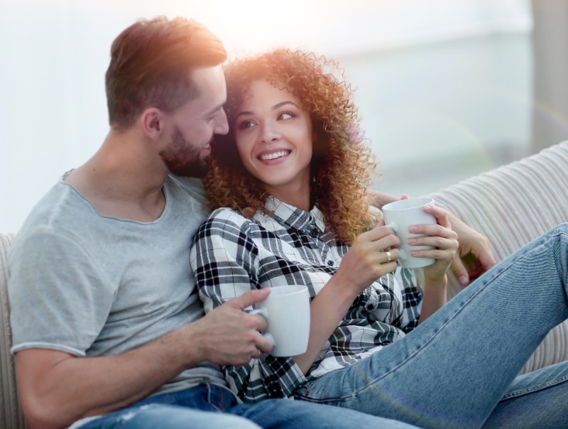 happy couple sitting on a sofa with coffee cups